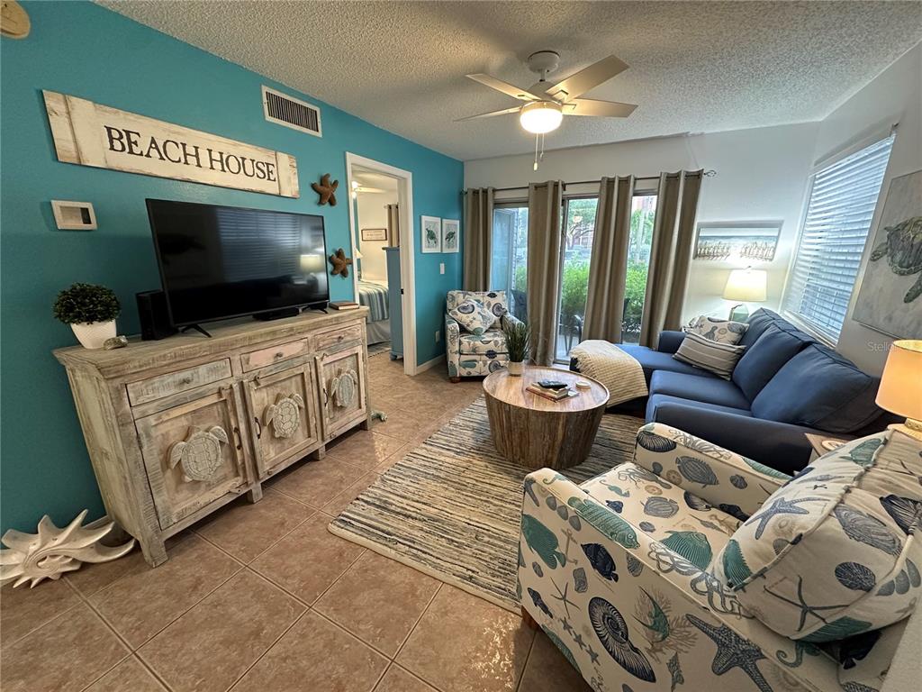 A living room features a blue accent wall, tile flooring, and coastal-themed furniture — 6825 STONES THROW CIRCLE N UNIT 1107, ST PETERSBURG, FL