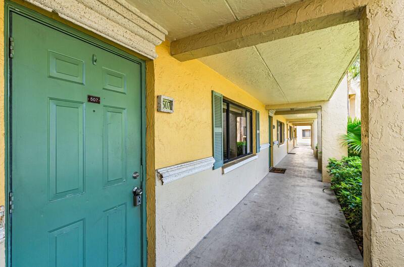 A green door labeled 507 opens onto a covered concrete walkway along a yellow building — 507 Meadows Circle, Boynton Beach FL 33436, BOYNTON BEACH, FL