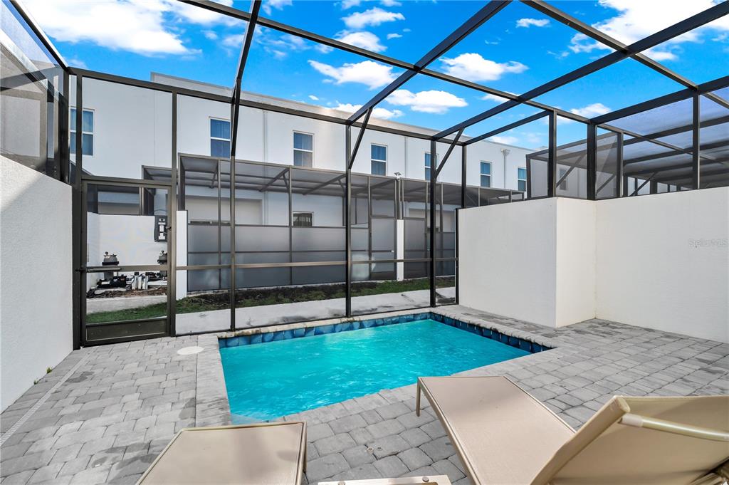 A small rectangular swimming pool sits on a paved patio enclosed by a screened lanai — 509 FAMAGUSTA DR., DAVENPORT, FL