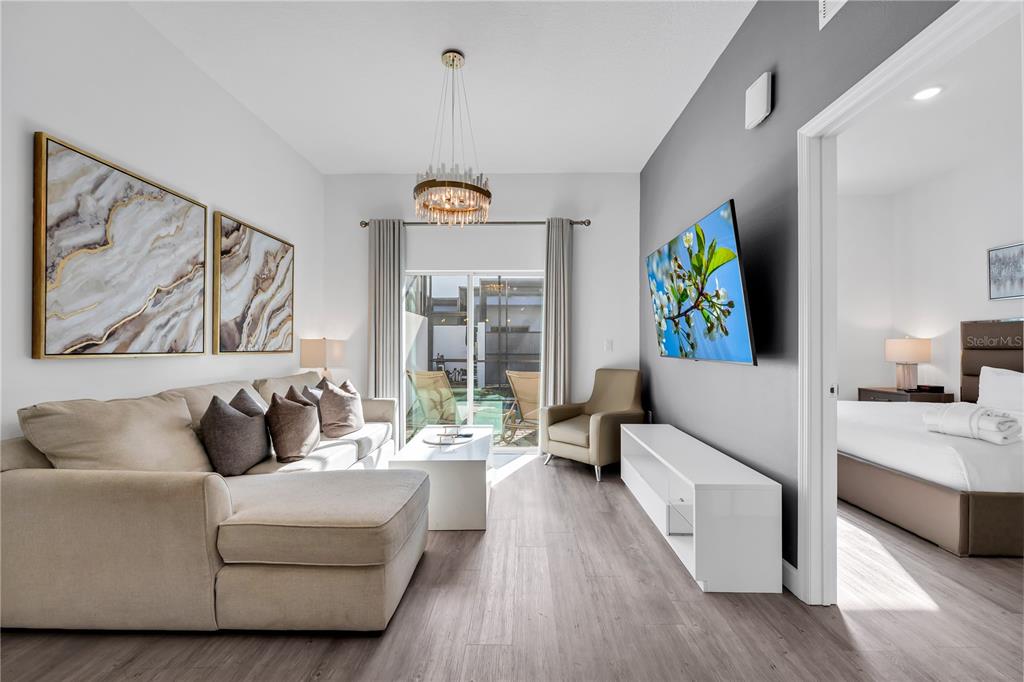 A living room with a sectional sofa, wall-mounted television, and an adjacent bedroom doorway — 509 FAMAGUSTA DR., DAVENPORT, FL