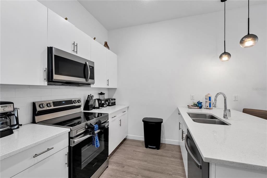 A modern kitchen features white cabinets, stainless steel appliances, and a white quartz island — 509 FAMAGUSTA DR., DAVENPORT, FL