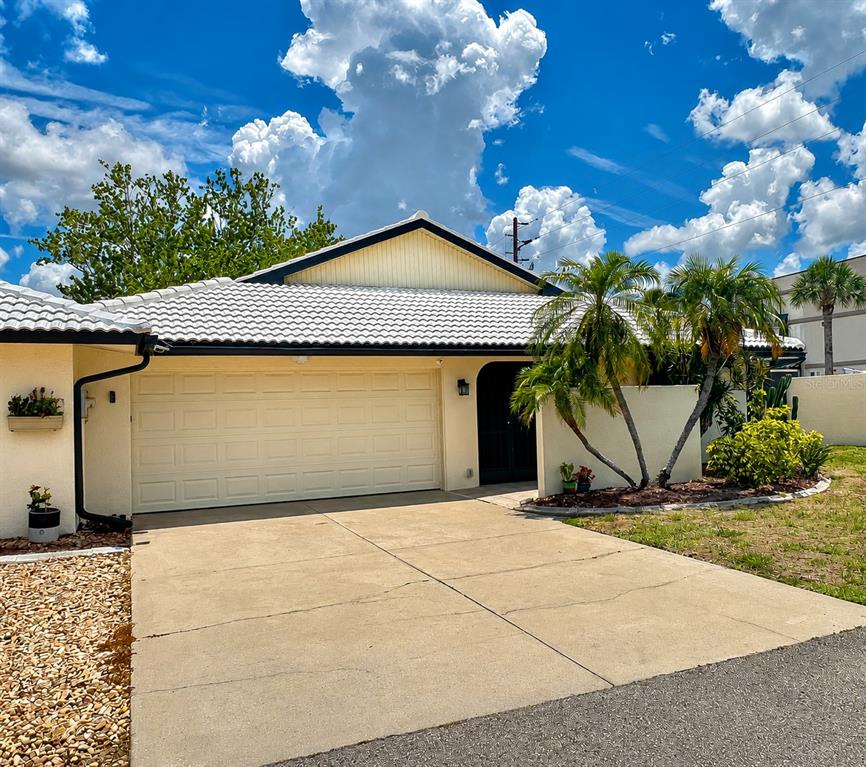 A single-story house with a white tile roof, a two-car garage, and palm trees — 14 IDLE SANDS DRIVE, VENICE, FL