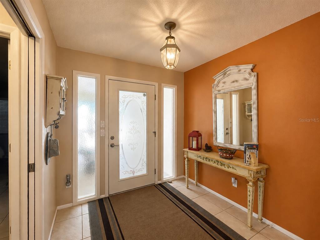 An entryway features a white front door with glass panels, tile flooring, and orange walls — 14 IDLE SANDS DRIVE, VENICE, FL