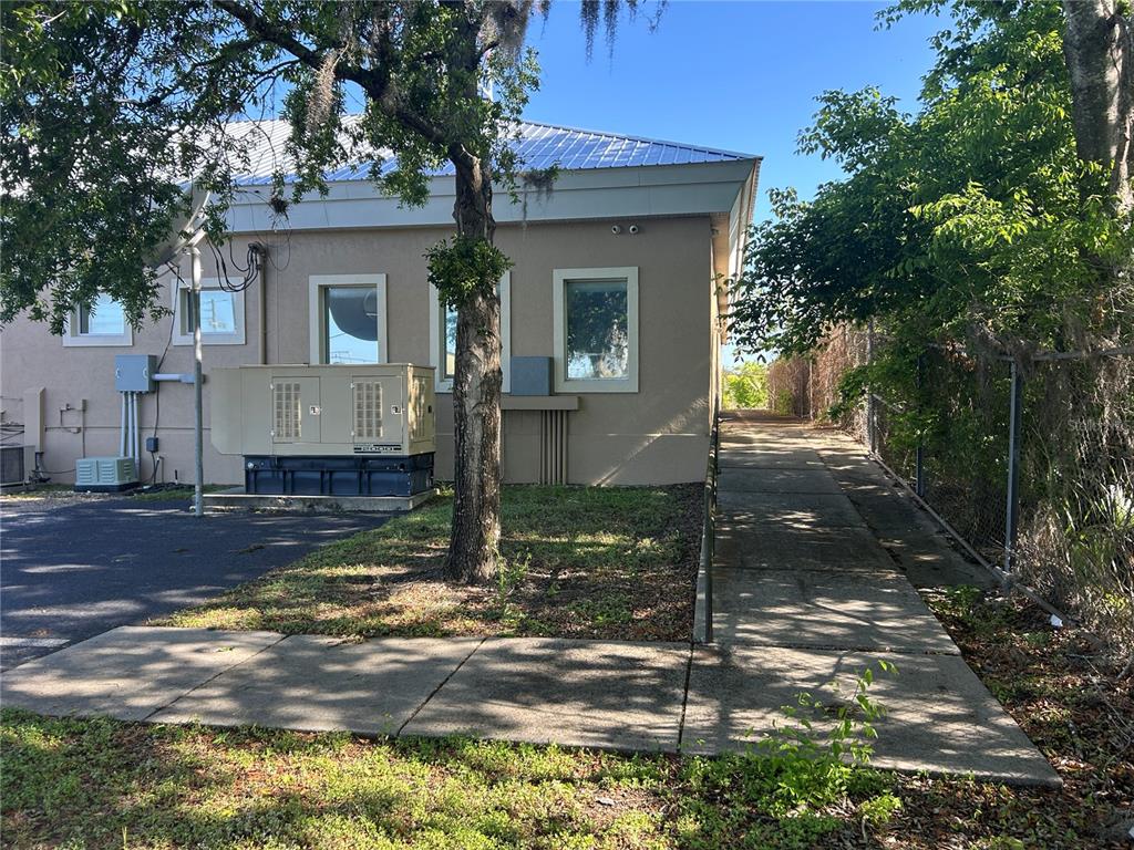 The exterior of a tan building features a large generator, a tree, and a concrete ramp — 1137 SW 7TH ROAD, OCALA, FL