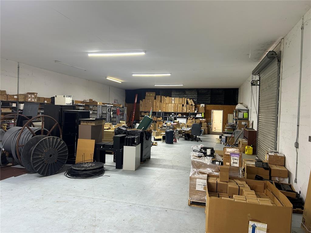 A large, industrial warehouse space features concrete floors, fluorescent lighting, and stacks of cardboard boxes — 1137 SW 7TH ROAD, OCALA, FL