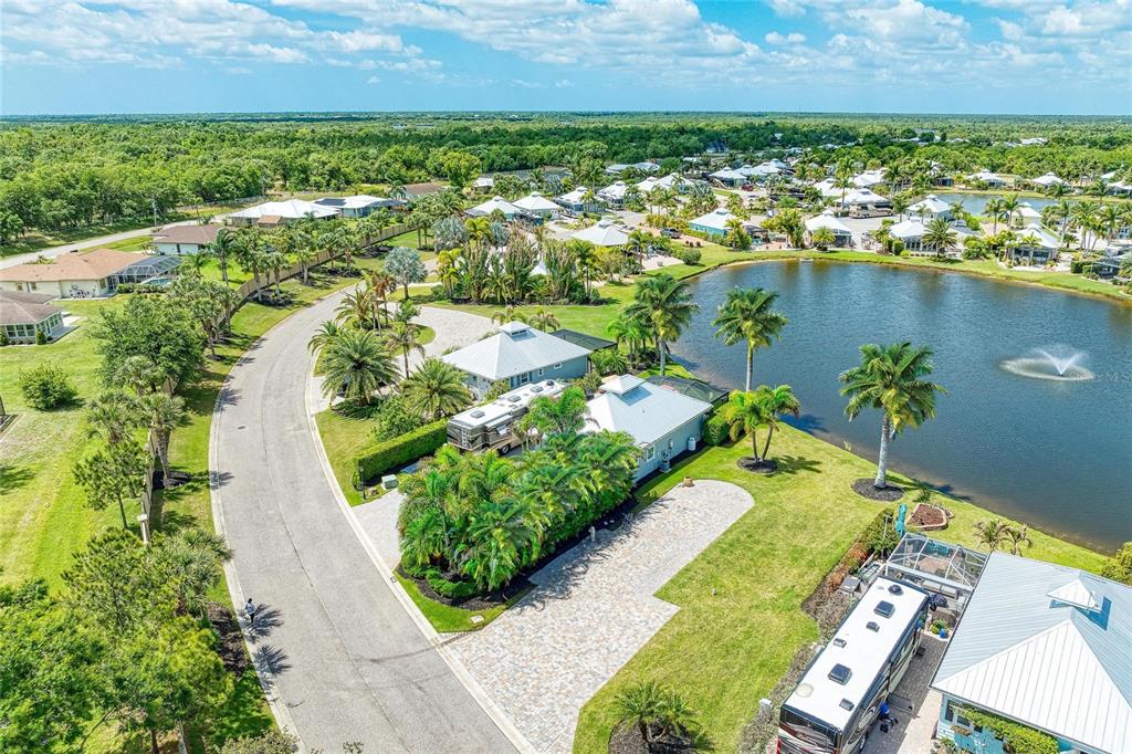 An aerial view shows a residential street with houses, palm trees, and a central pond — 8789 SW SAND CRANE CIRCLE LOT 38, ARCADIA, FL