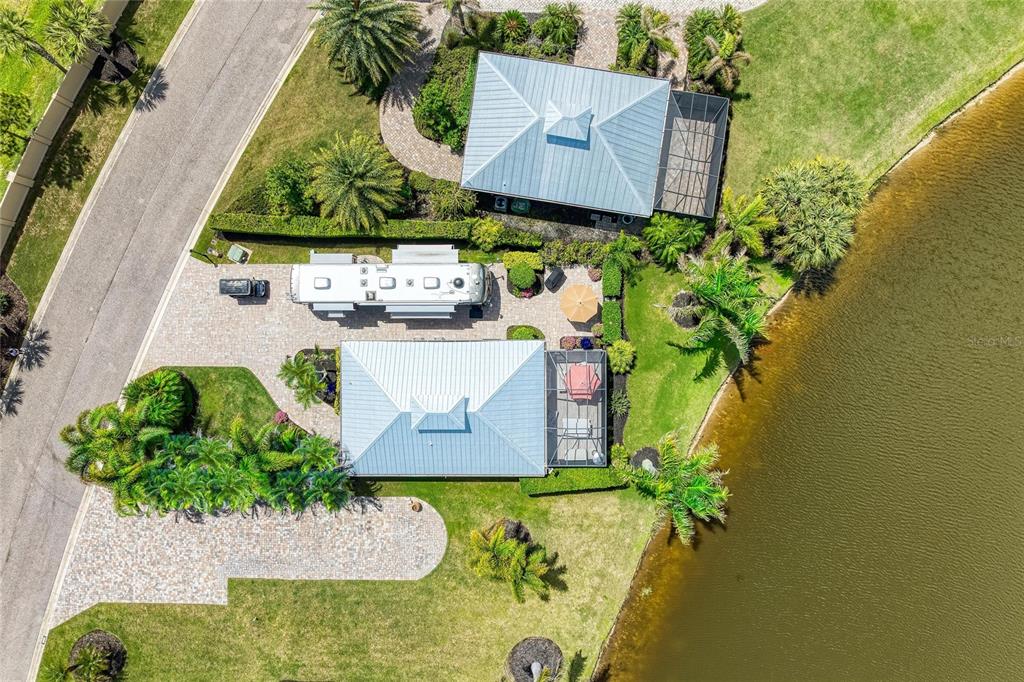 An aerial view shows two homes with metal roofs, a parked RV, and a lake — 8789 SW SAND CRANE CIRCLE LOT 38, ARCADIA, FL