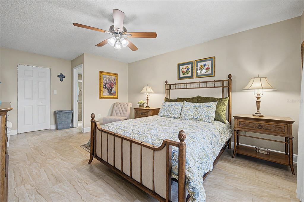 A bedroom features a wooden bed frame, tile flooring, a ceiling fan, and two nightstands — 9136 TIARA COURT, NEW PORT RICHEY, FL