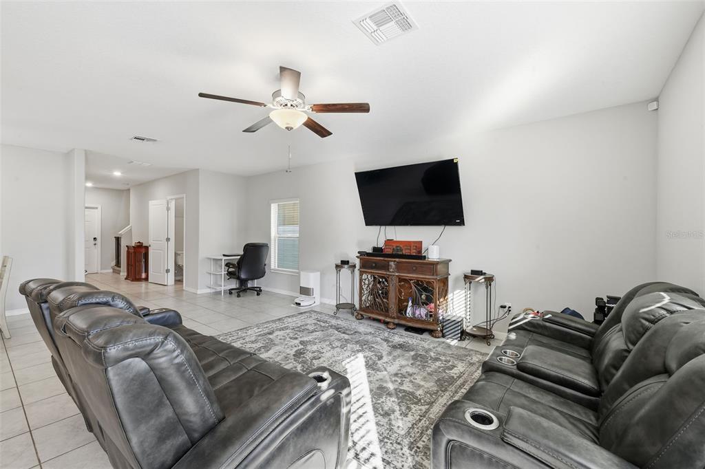 A living room features gray leather reclining sofas, a television, and a ceiling fan — 2007 SEA SALT COURT, RUSKIN, FL