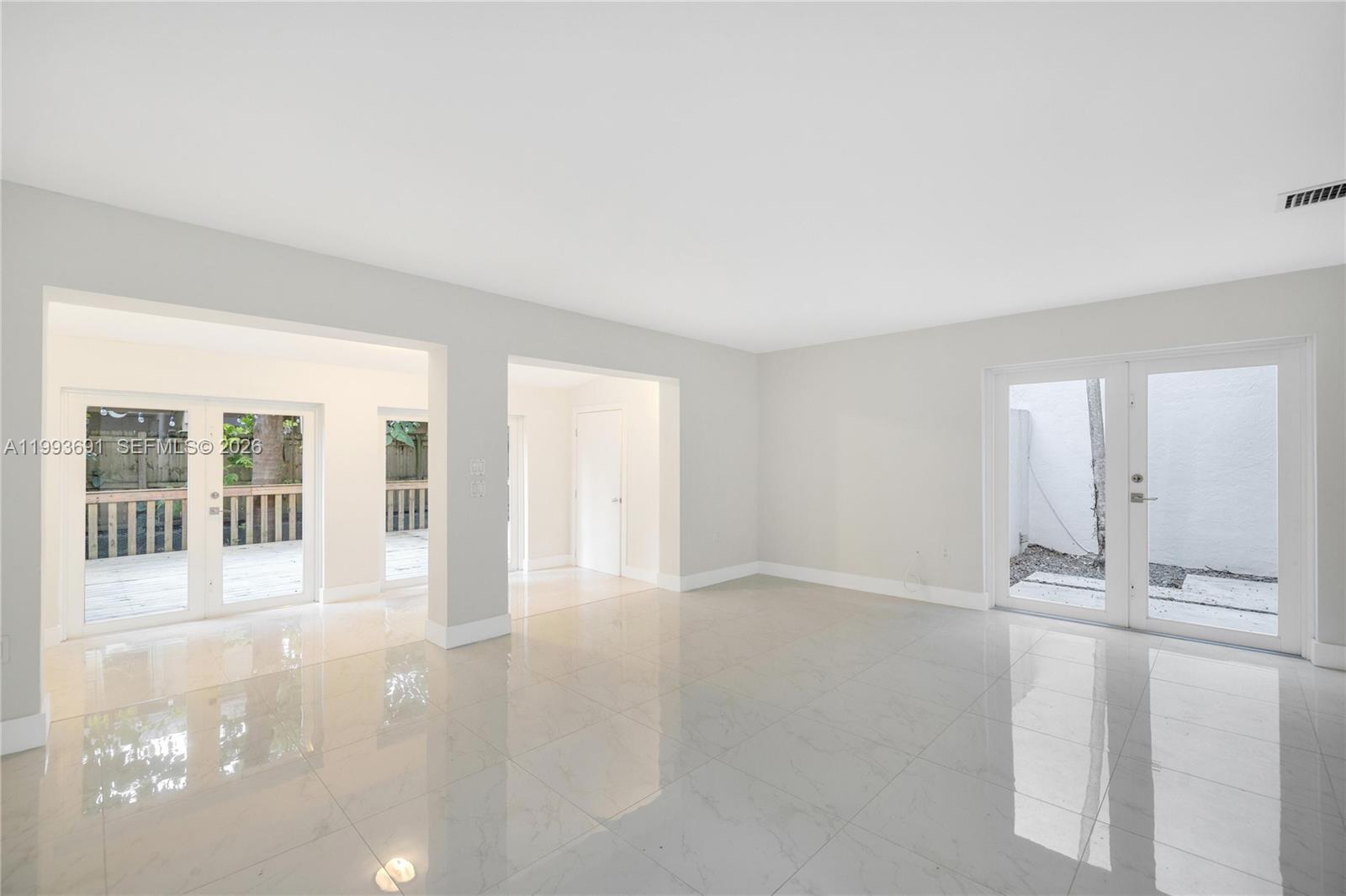 A bright, empty room features white tile flooring, light gray walls, and multiple glass doors — 3056 Shipping Ave # 2, Miami FL 33133, MIAMI, FL