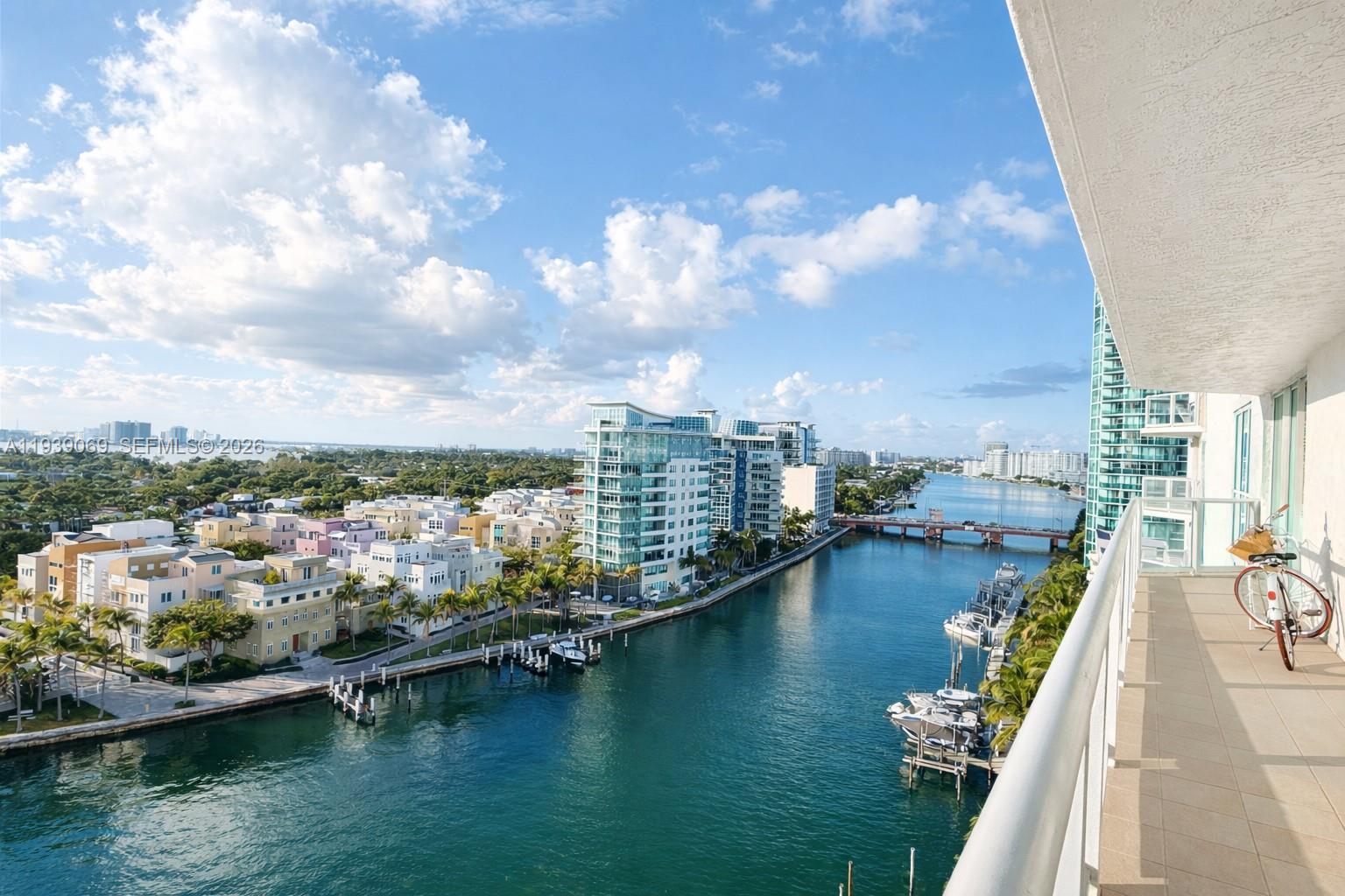 A high-angle view from a balcony overlooking a canal, boats, and modern residential buildings — 5900 Collins Ave # 1405, Miami Beach FL 33140, MIAMI BEACH, FL