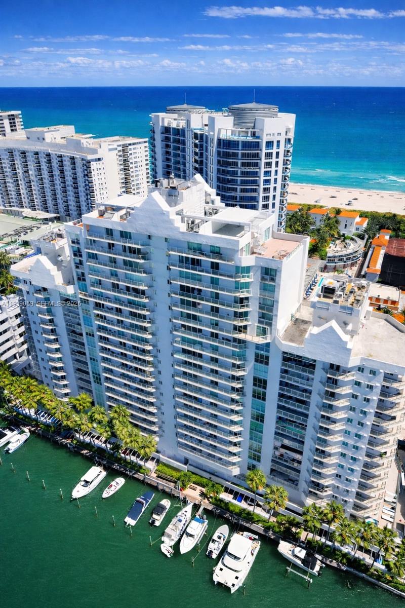 An aerial view of a white high-rise condominium building situated along a canal with boats — 5900 Collins Ave # 1405, Miami Beach FL 33140, MIAMI BEACH, FL
