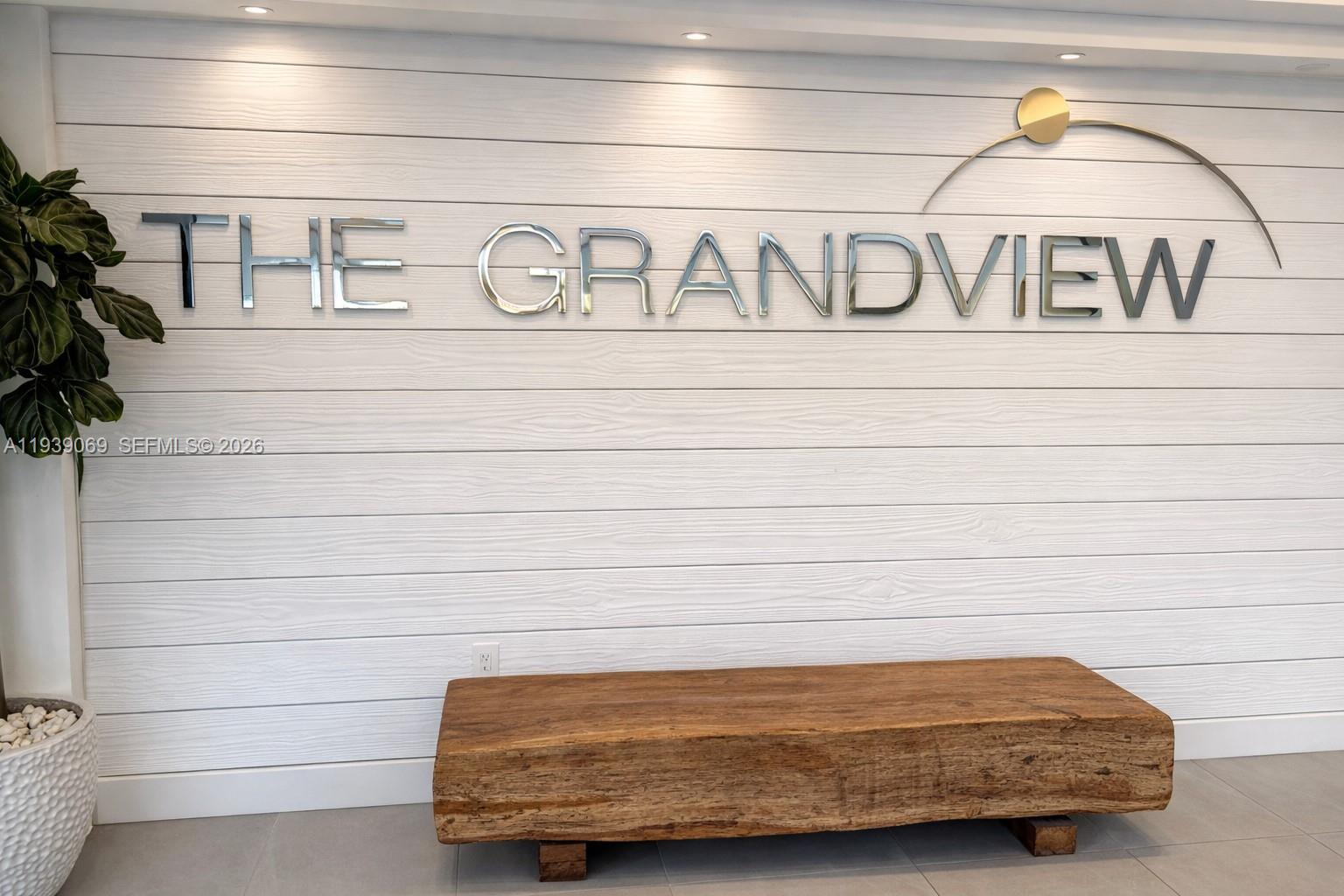 A wooden bench sits in front of a white shiplap wall with metallic lettering — 5900 Collins Ave # 1405, Miami Beach FL 33140, MIAMI BEACH, FL