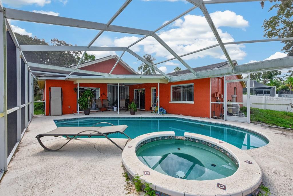 A screened-in patio features a swimming pool, a circular hot tub, and orange exterior walls — 4609 OAK RIVER CIRCLE, VALRICO, FL
