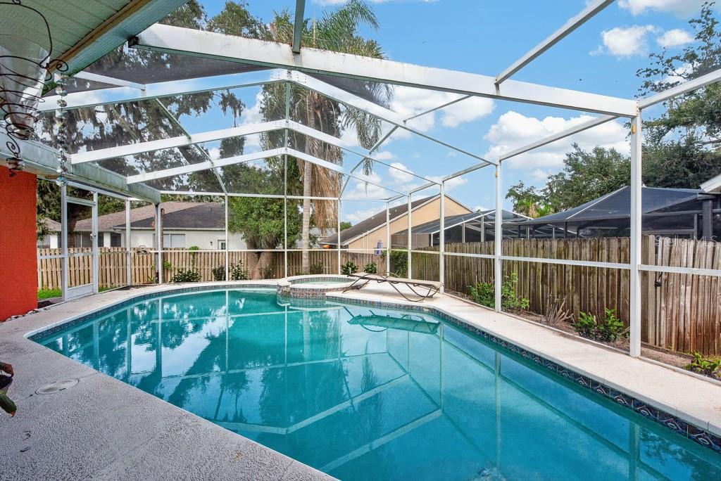 A screened-in swimming pool and hot tub sit on a concrete patio in a backyard — 4609 OAK RIVER CIRCLE, VALRICO, FL