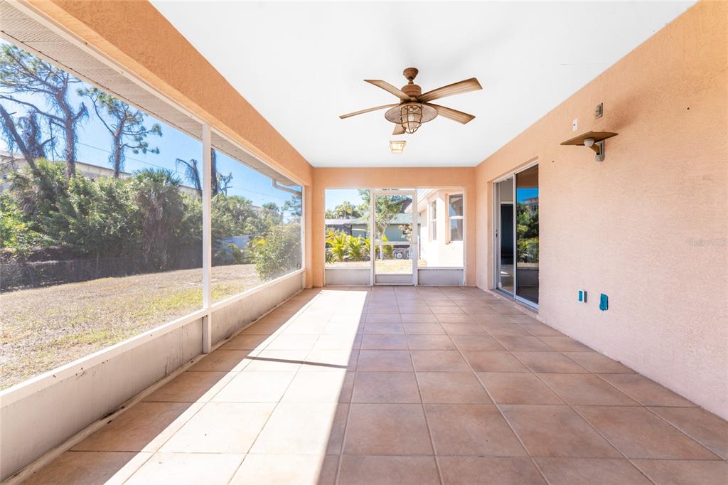 A screened-in patio with tile flooring, a ceiling fan, and views of a grassy yard — 1053 BAY HARBOR DRIVE, ENGLEWOOD, FL