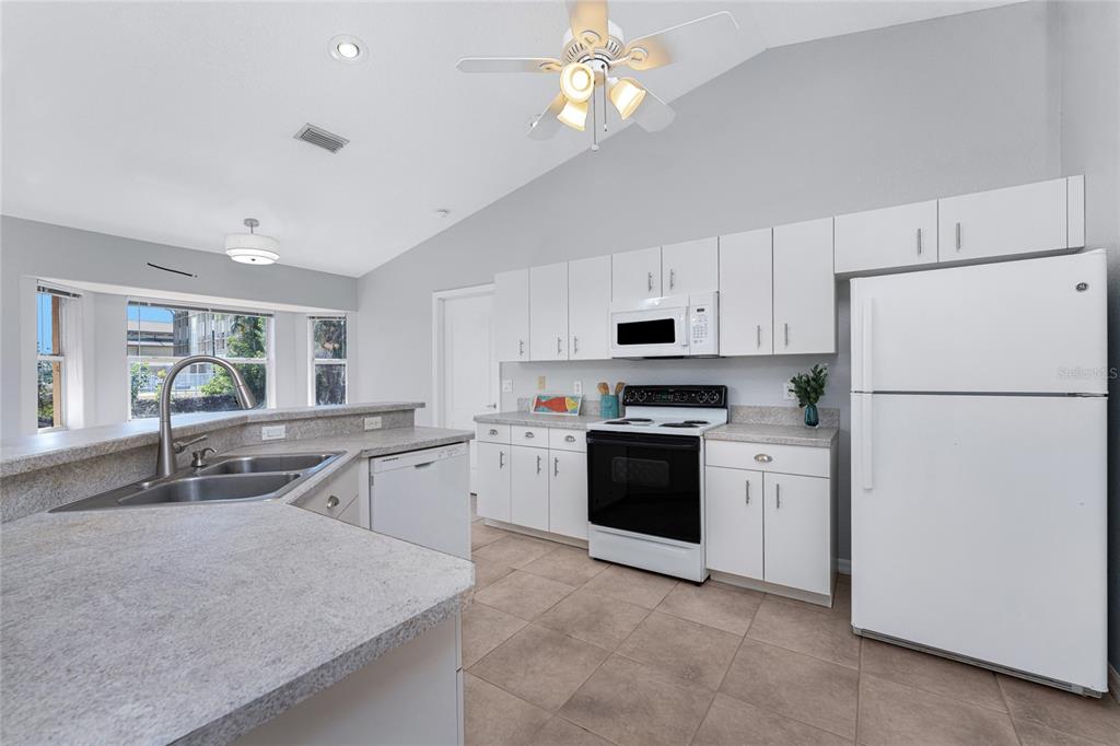 A kitchen with white cabinets, light countertops, tile flooring, and a white refrigerator — 1053 BAY HARBOR DRIVE, ENGLEWOOD, FL