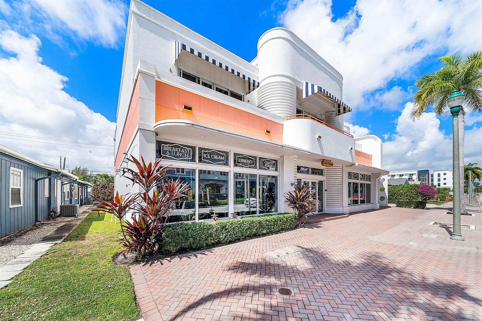 A two-story commercial building with an orange facade, striped awnings, and a brick-paved sidewalk — 124 NE 5th Avenue, Delray Beach FL 33483, DELRAY BEACH, FL