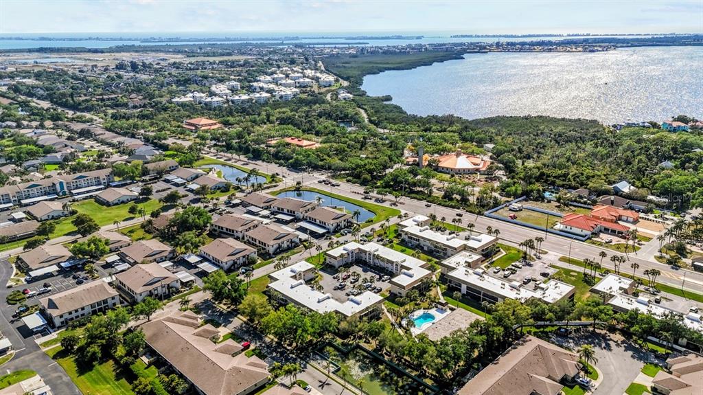 An aerial view shows a residential complex with multiple buildings, parking lots, and nearby water — 2727 75TH STREET W UNIT 8A2, BRADENTON, FL