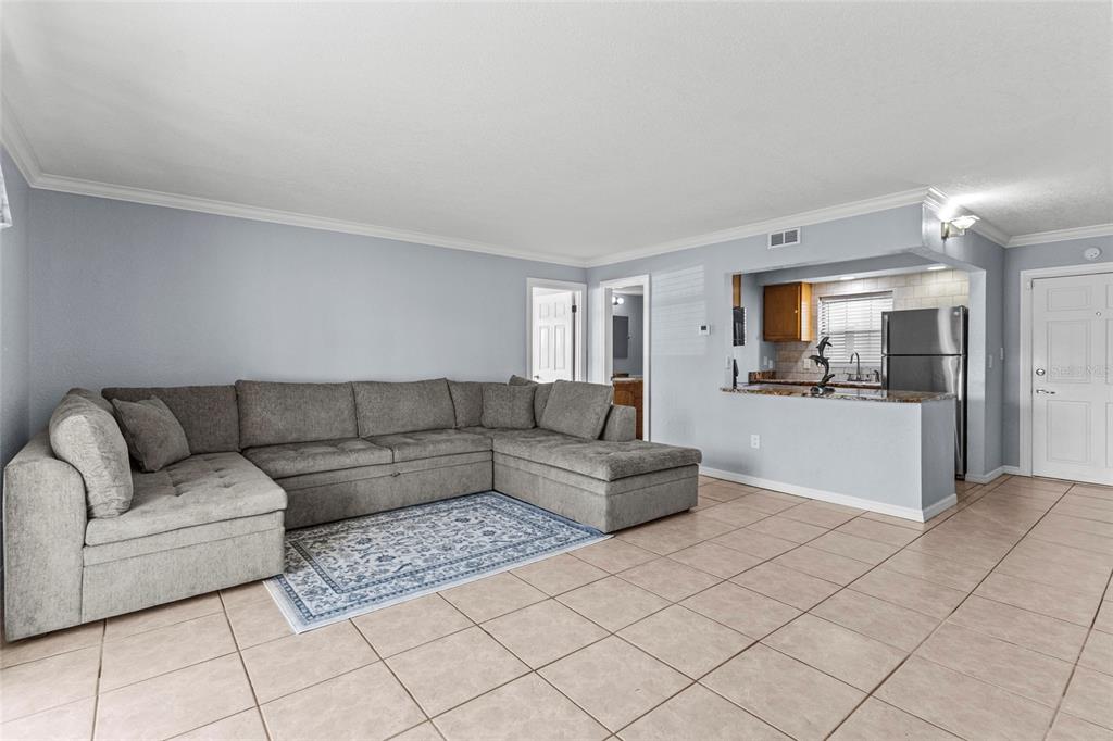 A living room with a large gray sectional sofa, a patterned rug, and tile flooring — 2727 75TH STREET W UNIT 8A2, BRADENTON, FL