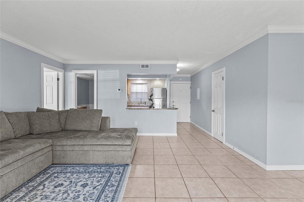 A living room with light blue walls, tile flooring, and a view into the kitchen — 2727 75TH STREET W UNIT 8A2, BRADENTON, FL