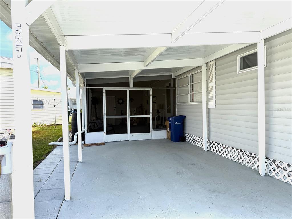 A covered concrete carport leads to a screened-in porch area with white siding — 527 BLACKBURN BOULEVARD, NORTH PORT, FL