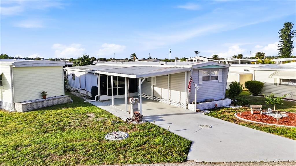 An exterior view of a light-colored mobile home with a carport and a paved driveway — 527 BLACKBURN BOULEVARD, NORTH PORT, FL
