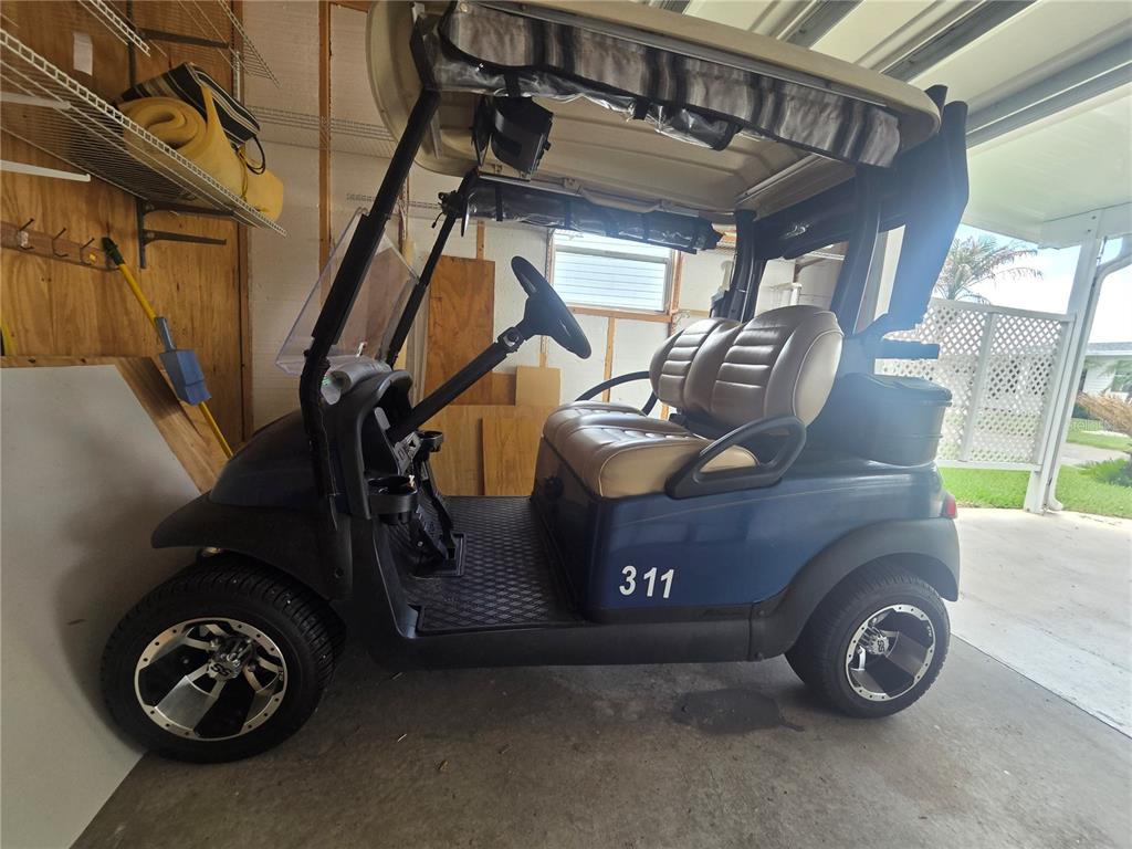 A blue golf cart with tan seats and custom wheels is parked inside a garage — 311 TOWNBRIDGE DRIVE, HAINES CITY, FL