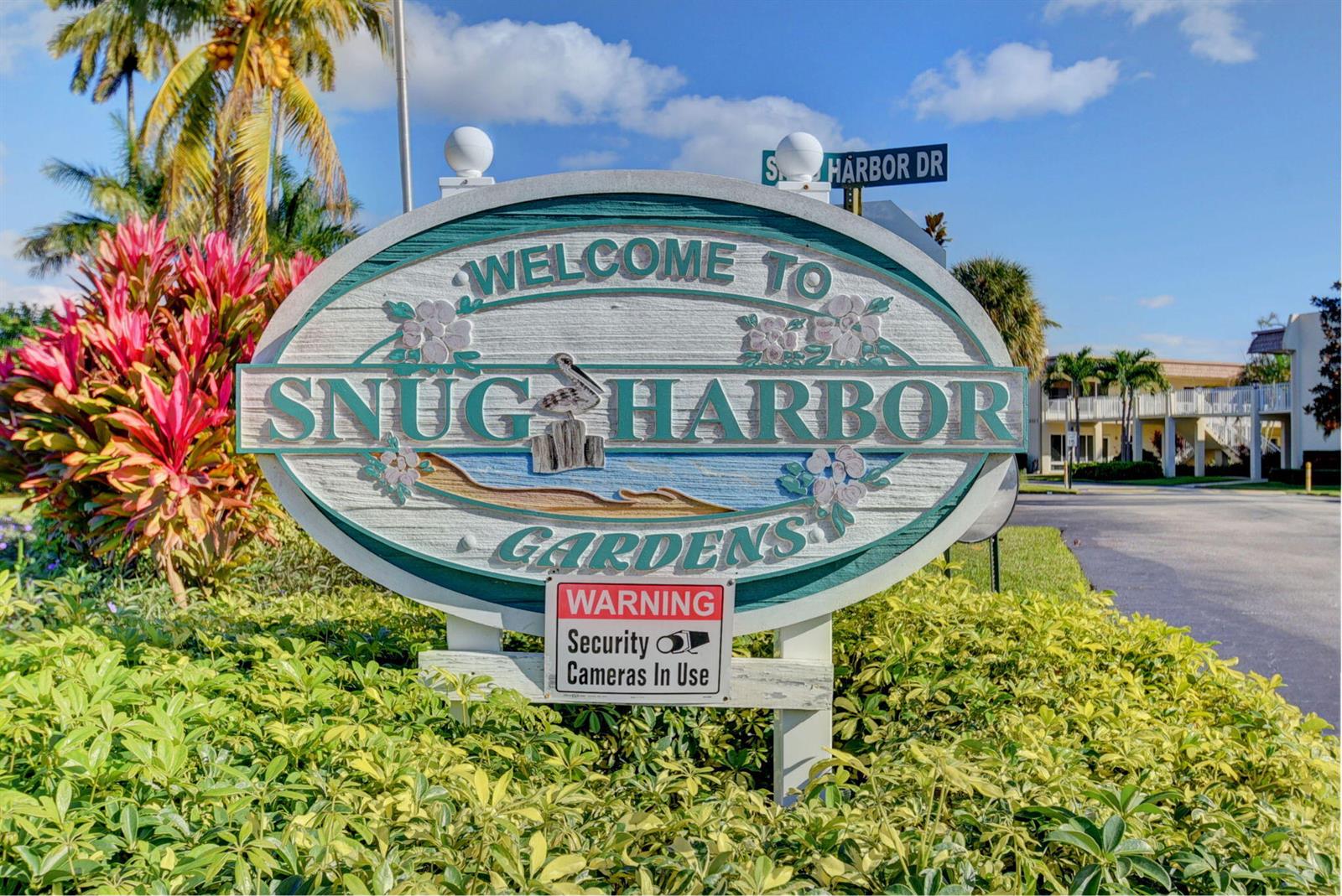 A sign for Snug Harbor Gardens stands in front of a landscaped residential area — 600 Snug Harbor Drive # A16, Boynton Beach FL 33435, BOYNTON BEACH, FL