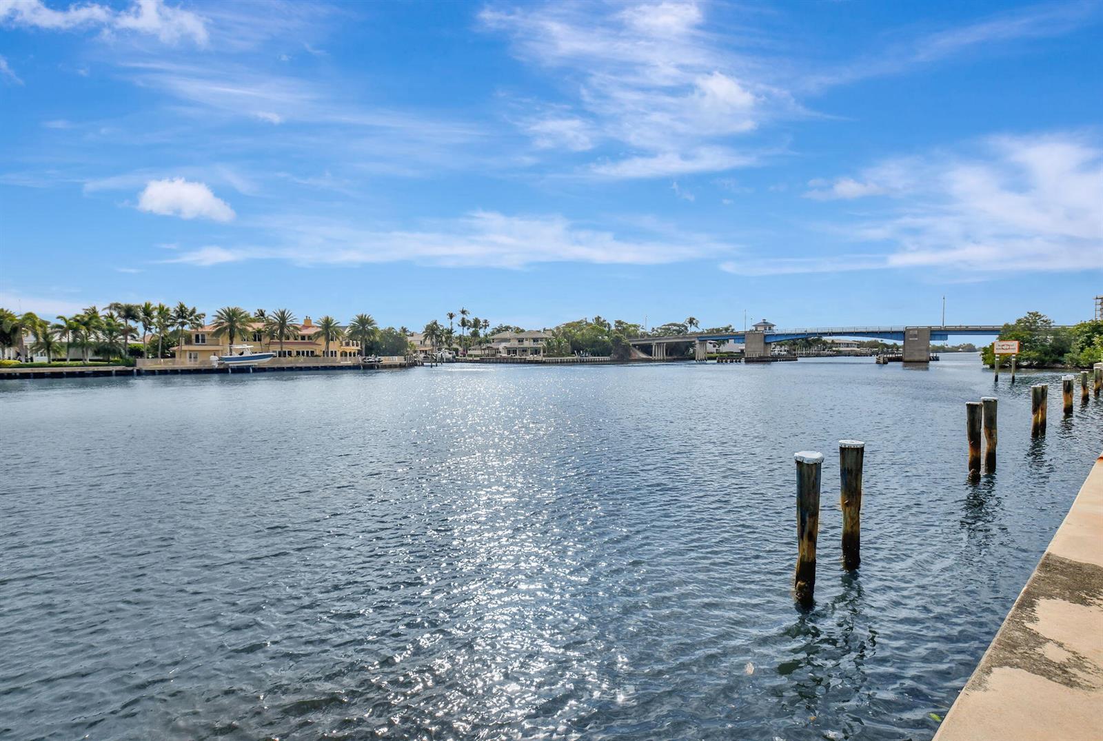 A view of a waterway with wooden pilings, waterfront homes, and a bridge — 600 Snug Harbor Drive # A16, Boynton Beach FL 33435, BOYNTON BEACH, FL