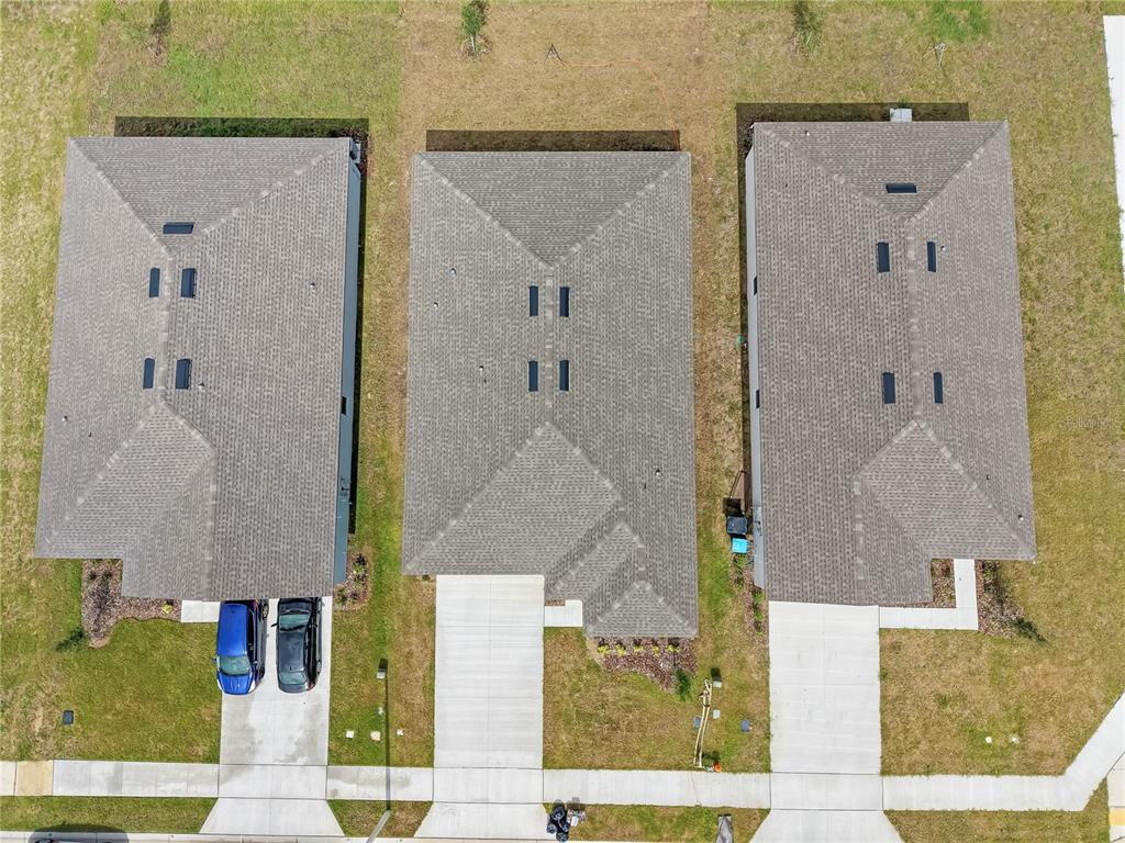 An aerial view shows three suburban houses with gray shingled roofs and concrete driveways — 3008 DAFFODIL DRIVE, LAKE HAMILTON, FL