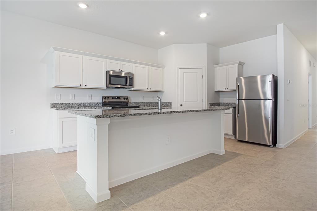 A kitchen features white cabinets, granite countertops, stainless steel appliances, and a central island — 3008 DAFFODIL DRIVE, LAKE HAMILTON, FL
