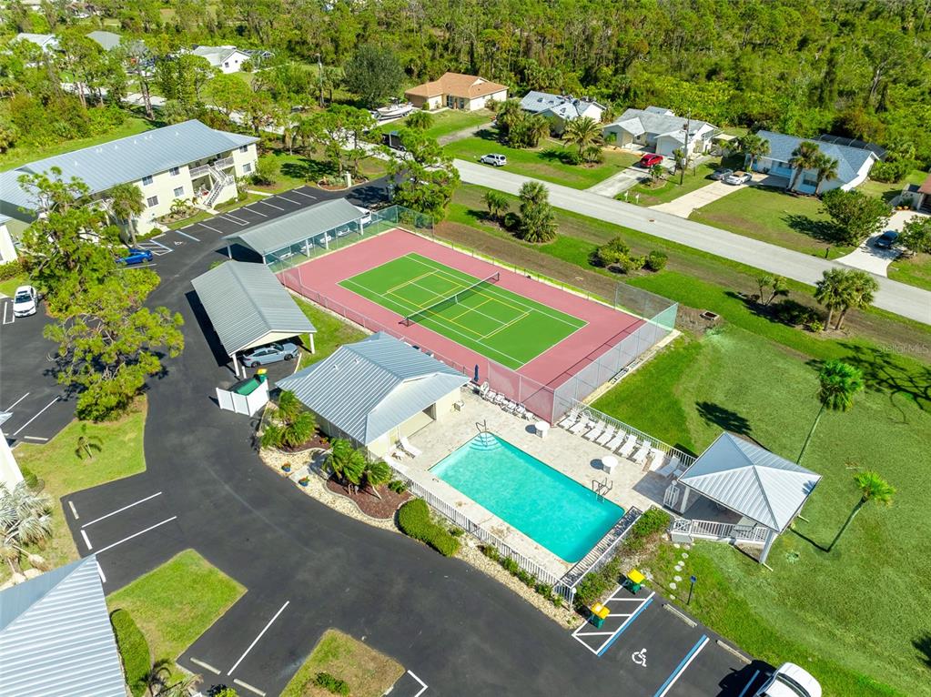 An aerial view shows a tennis court, a swimming pool, and covered parking areas — 6600 GASPARILLA PINES BOULEVARD UNIT 204, ENGLEWOOD, FL