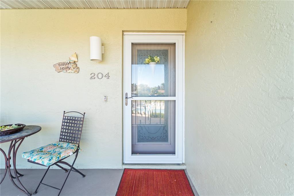 A patio features a small table, a patterned chair, and a door marked 204 — 6600 GASPARILLA PINES BOULEVARD UNIT 204, ENGLEWOOD, FL