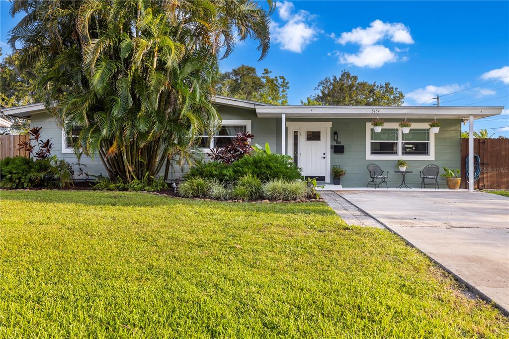 A single-story house with green siding, a white front door, and a large palm tree — 5154 33RD AVENUE N, ST PETERSBURG, FL