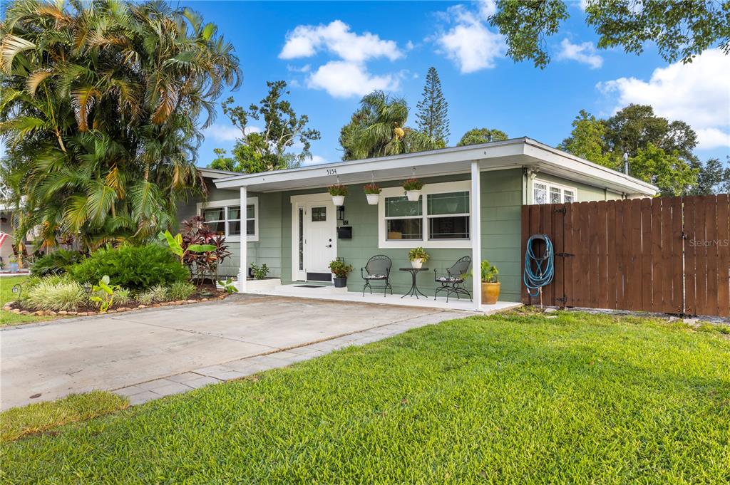 A single-story house with green siding, a covered front porch, and a wooden privacy fence — 5154 33RD AVENUE N, ST PETERSBURG, FL