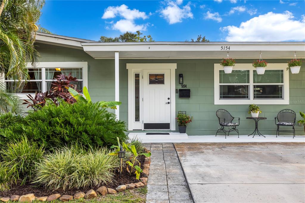 The exterior of a green house features a white front door and a concrete driveway — 5154 33RD AVENUE N, ST PETERSBURG, FL