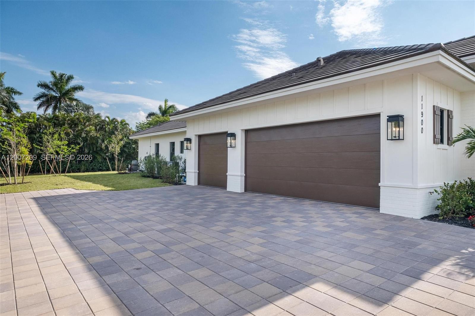 A house exterior features a paved driveway, two brown garage doors, and white siding — 11900 SW 14th Pl, Davie FL 33325, DAVIE, FL