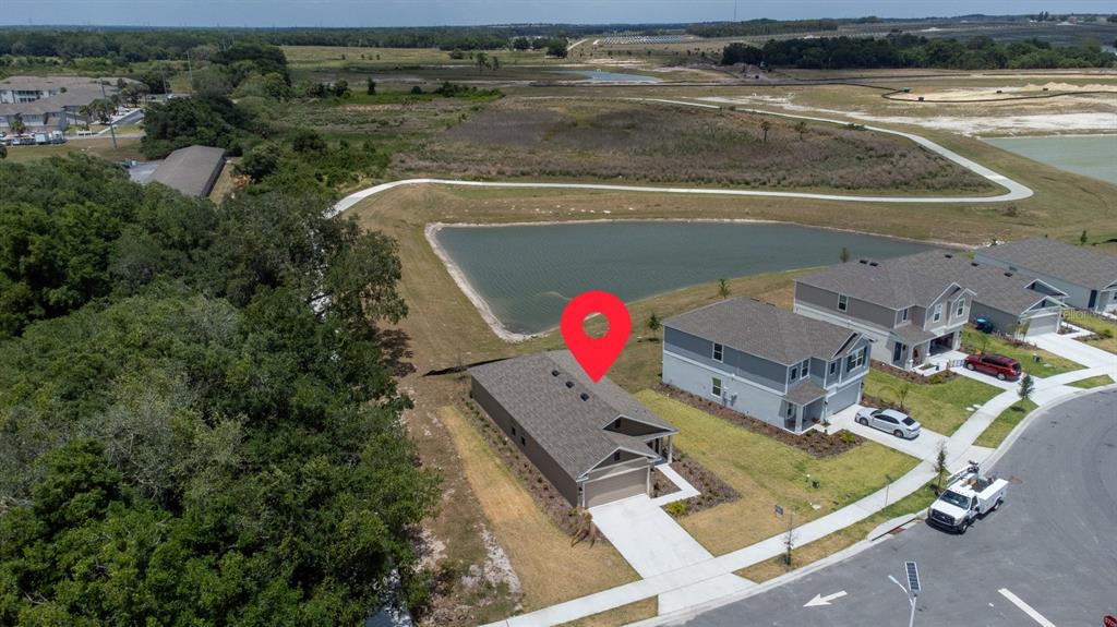 An aerial view shows a single-story house with a garage next to a retention pond — 573 BELL PRAIRIE CIRCLE, LAKE WALES, FL