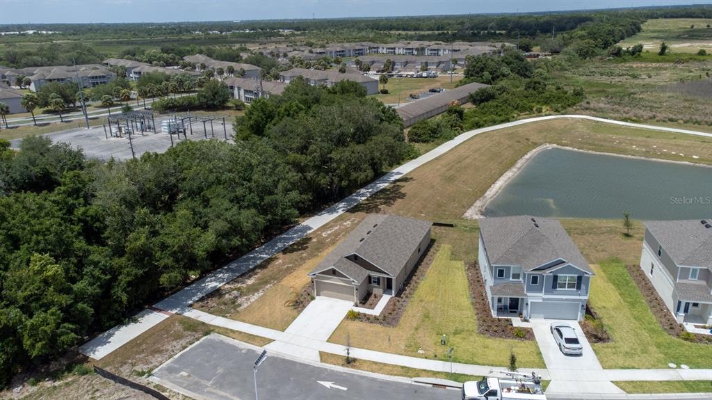 An aerial view shows two suburban houses next to a retention pond and wooded area — 573 BELL PRAIRIE CIRCLE, LAKE WALES, FL