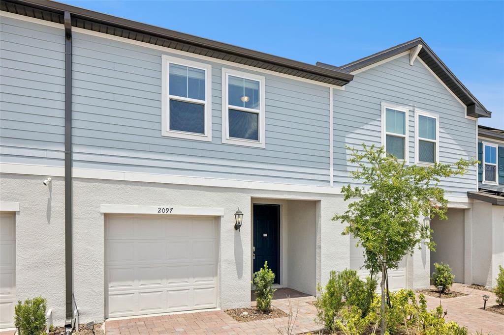A two-story townhouse exterior features light blue horizontal siding, a garage, and a front entrance — 2097 CRAPE JASMINE LANE, ORLANDO, FL