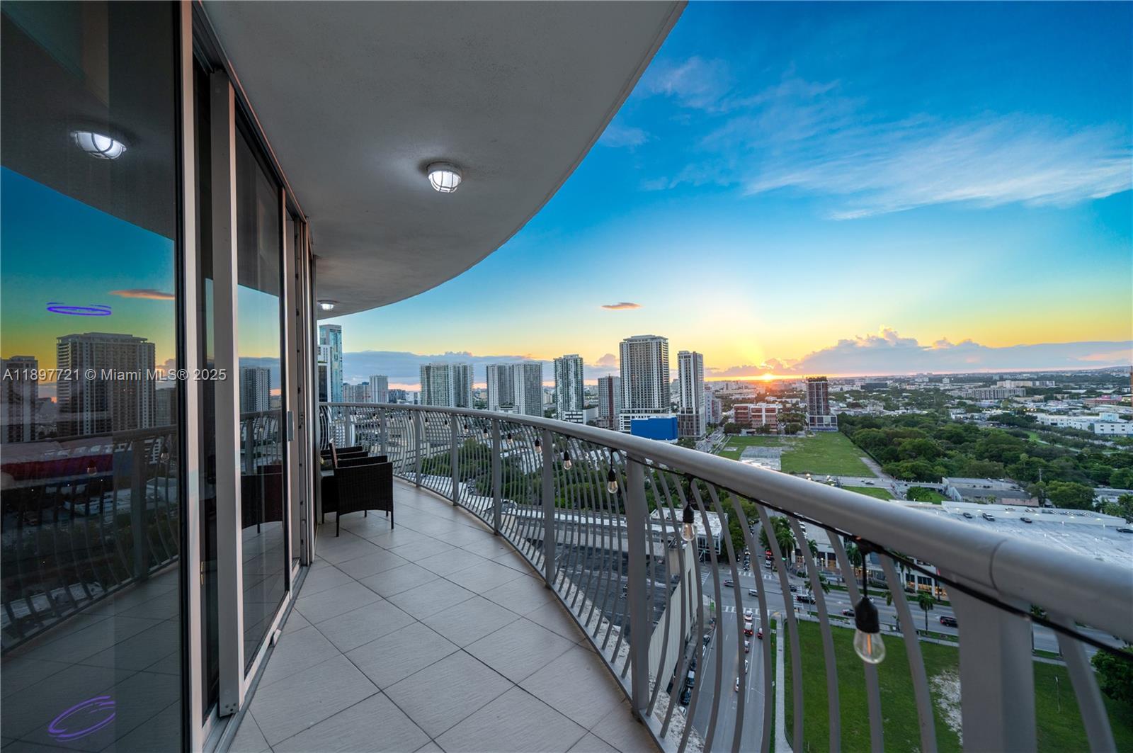 A curved balcony with tile flooring overlooks a city skyline at sunset — 1750 N Bayshore Dr # 2615, Miami FL 33132, MIAMI, FL