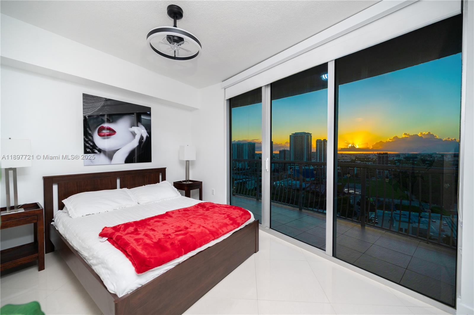 A bedroom features a platform bed, red throw, wall art, and floor-to-ceiling windows with sunset views — 1750 N Bayshore Dr # 2615, Miami FL 33132, MIAMI, FL