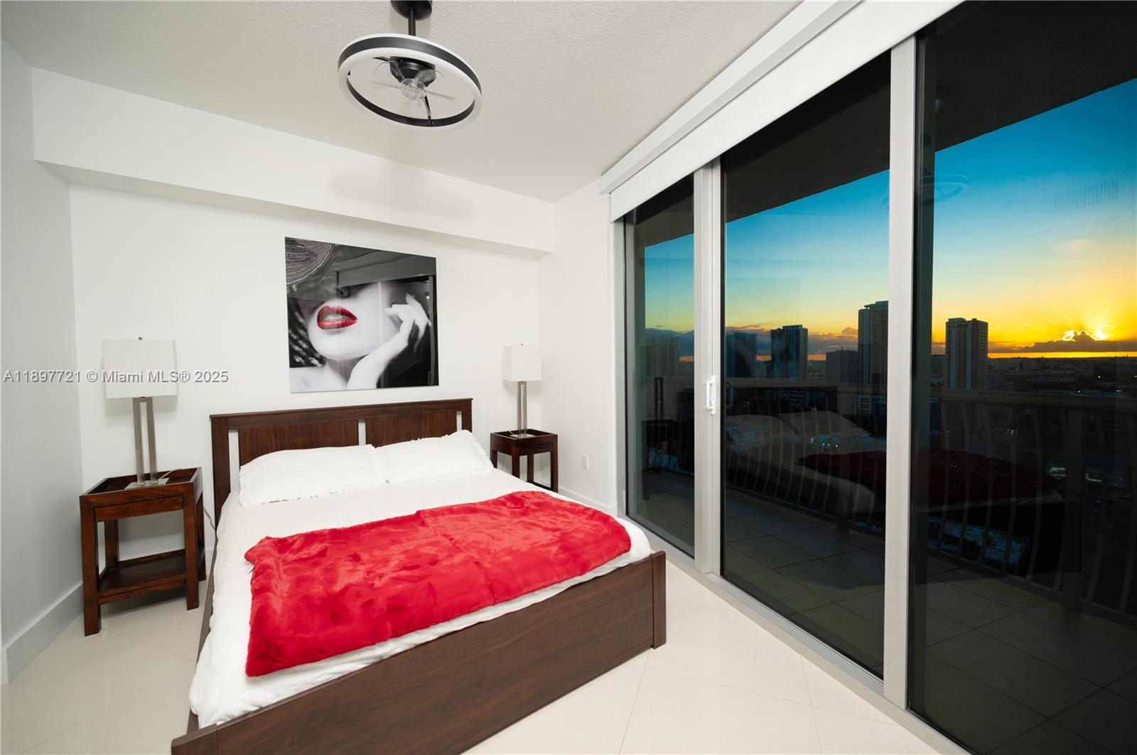 A bedroom features a dark wood bed, red throw, and floor-to-ceiling windows overlooking a sunset — 1750 N Bayshore Dr # 2615, Miami FL 33132, MIAMI, FL
