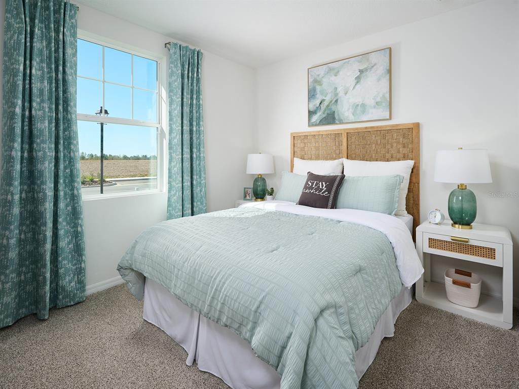 A bedroom features a woven headboard, light green bedding, and curtains overlooking a field — 7737 SATTERFIELD TERRACE, PARRISH, FL