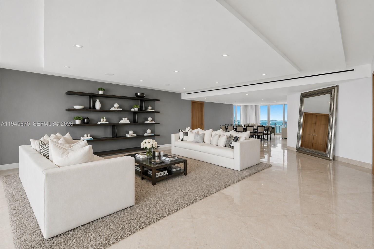 A living room features white sofas, a dark wood coffee table, and open wall shelving — 1643 Brickell Ave # 3904, Miami FL 33129, MIAMI, FL