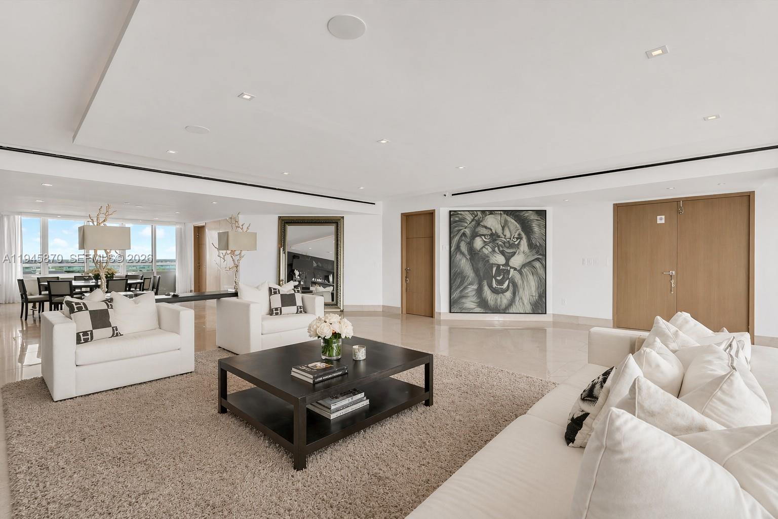 A spacious living room features white furniture, a dark coffee table, and a large lion painting — 1643 Brickell Ave # 3904, Miami FL 33129, MIAMI, FL