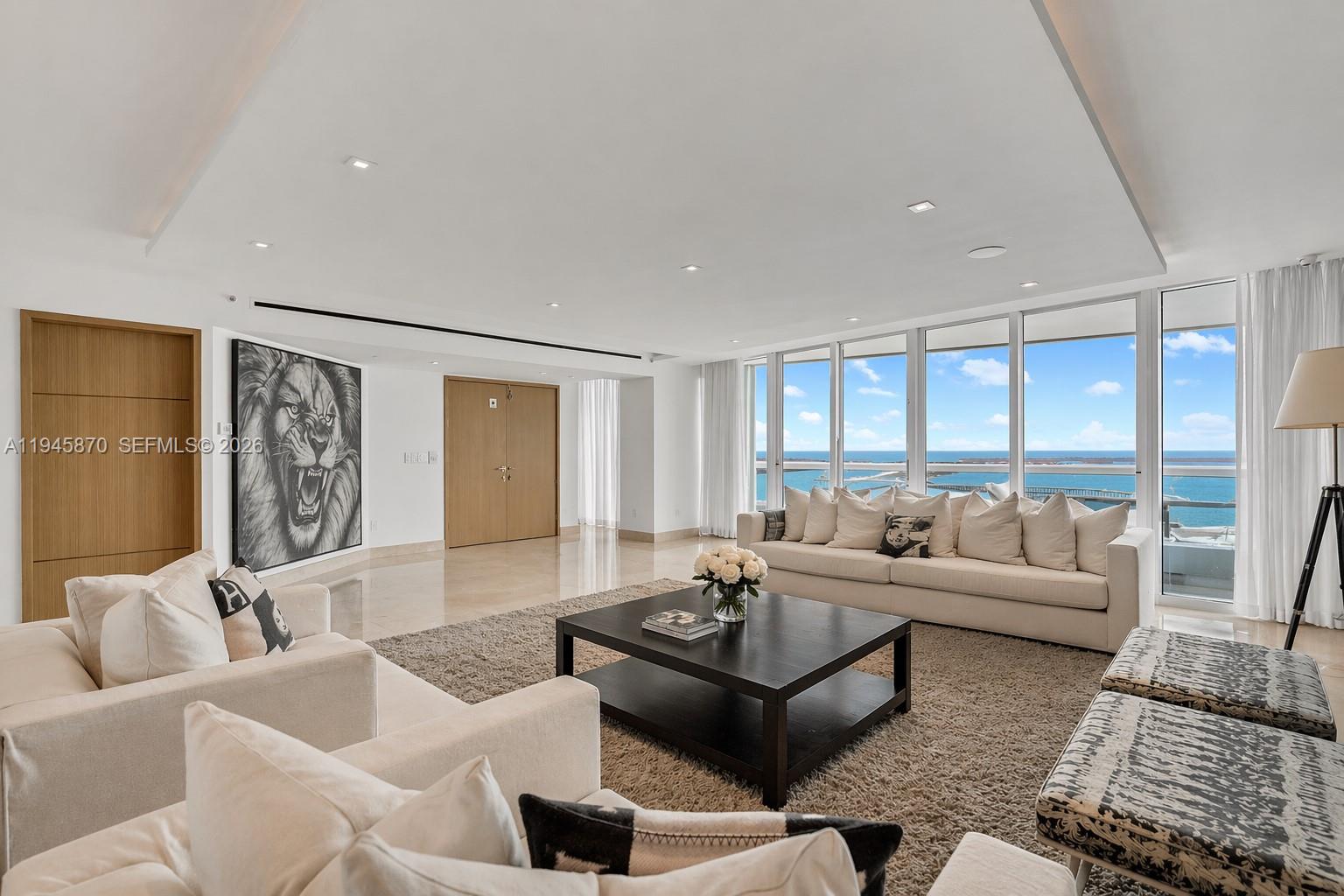 A modern living room features a large lion portrait, white sofas, and floor-to-ceiling ocean views — 1643 Brickell Ave # 3904, Miami FL 33129, MIAMI, FL