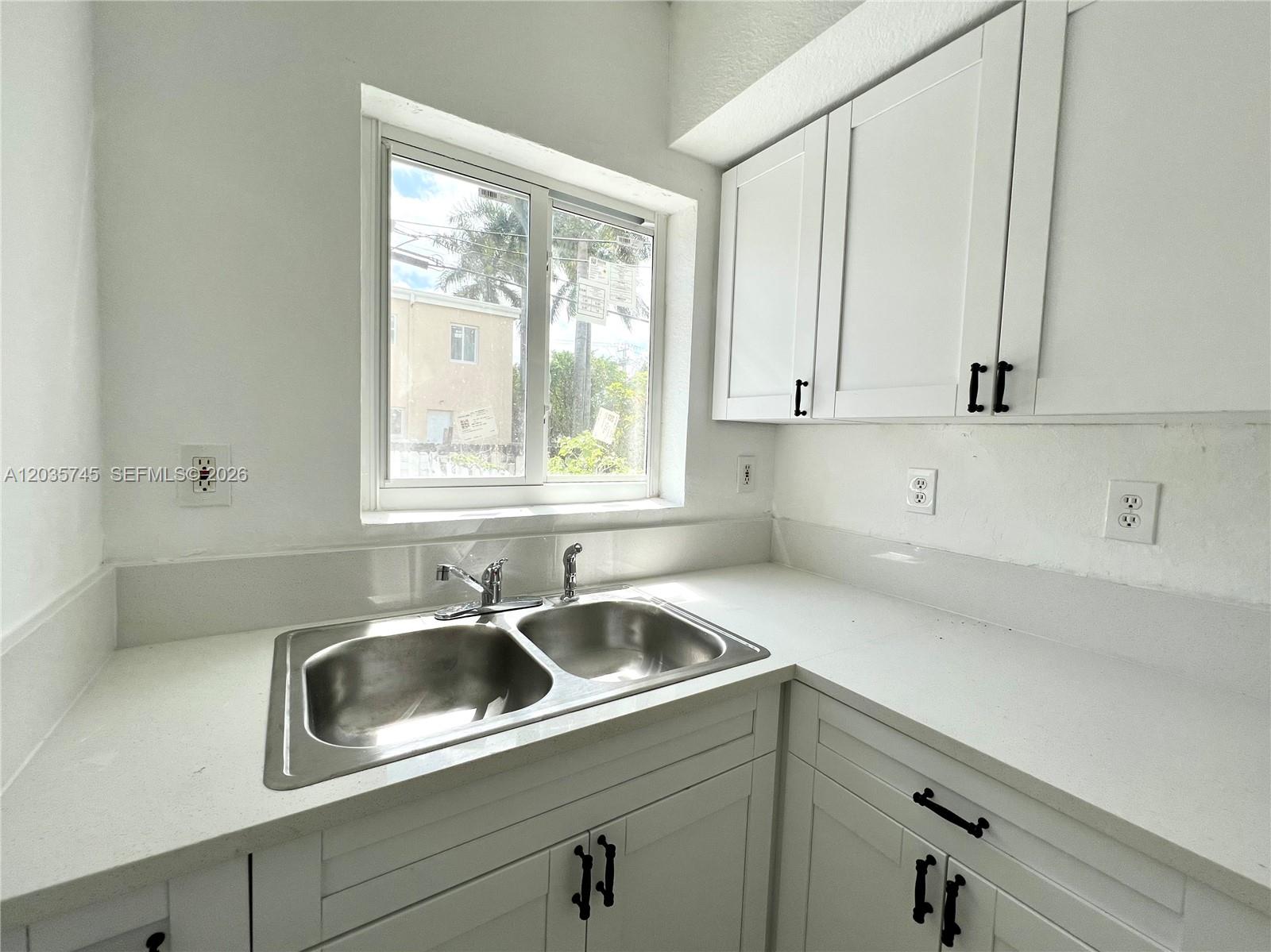 A kitchen features white cabinets, a double stainless steel sink, and a window above counters — 444 NW 84th St # 444, Miami FL 33150, MIAMI, FL