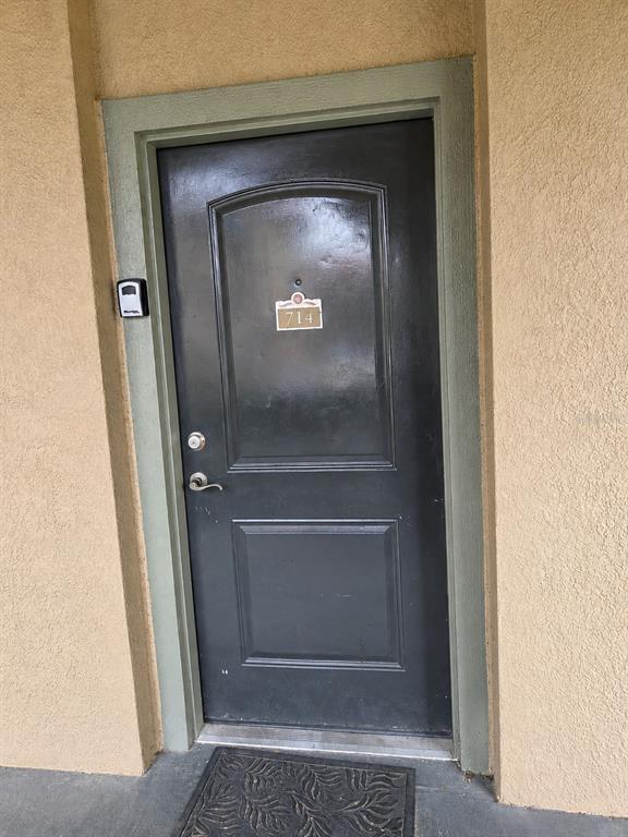 A dark-colored front door with a number plate and a lockbox on the exterior wall — 901 CHARO PARKWAY UNIT 714, DAVENPORT, FL